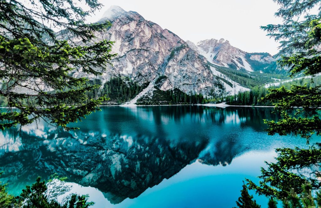 Ein idyllischer Bergsee mit atemberaubenden Spiegelungen in Prags, Italien, umgeben von Bäumen.
